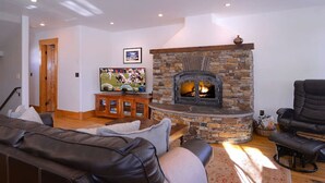 A living room with a stone fireplace, leather sofa, and a television. - Perfect spot for your group in Crested Butte! Convenient, walkable, pet friendly (Crested Butte)