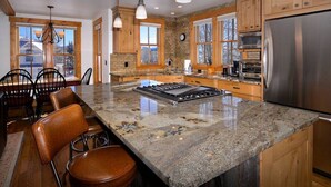 A kitchen with a large island, wooden cabinets, and a stainless steel refrigerator. - Perfect spot for your group in Crested Butte! Convenient, walkable, pet friendly (Crested Butte)