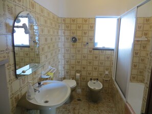 Une salle de bain équipée d’un lavabo, de toilettes, d’un bidet et d’un miroir.