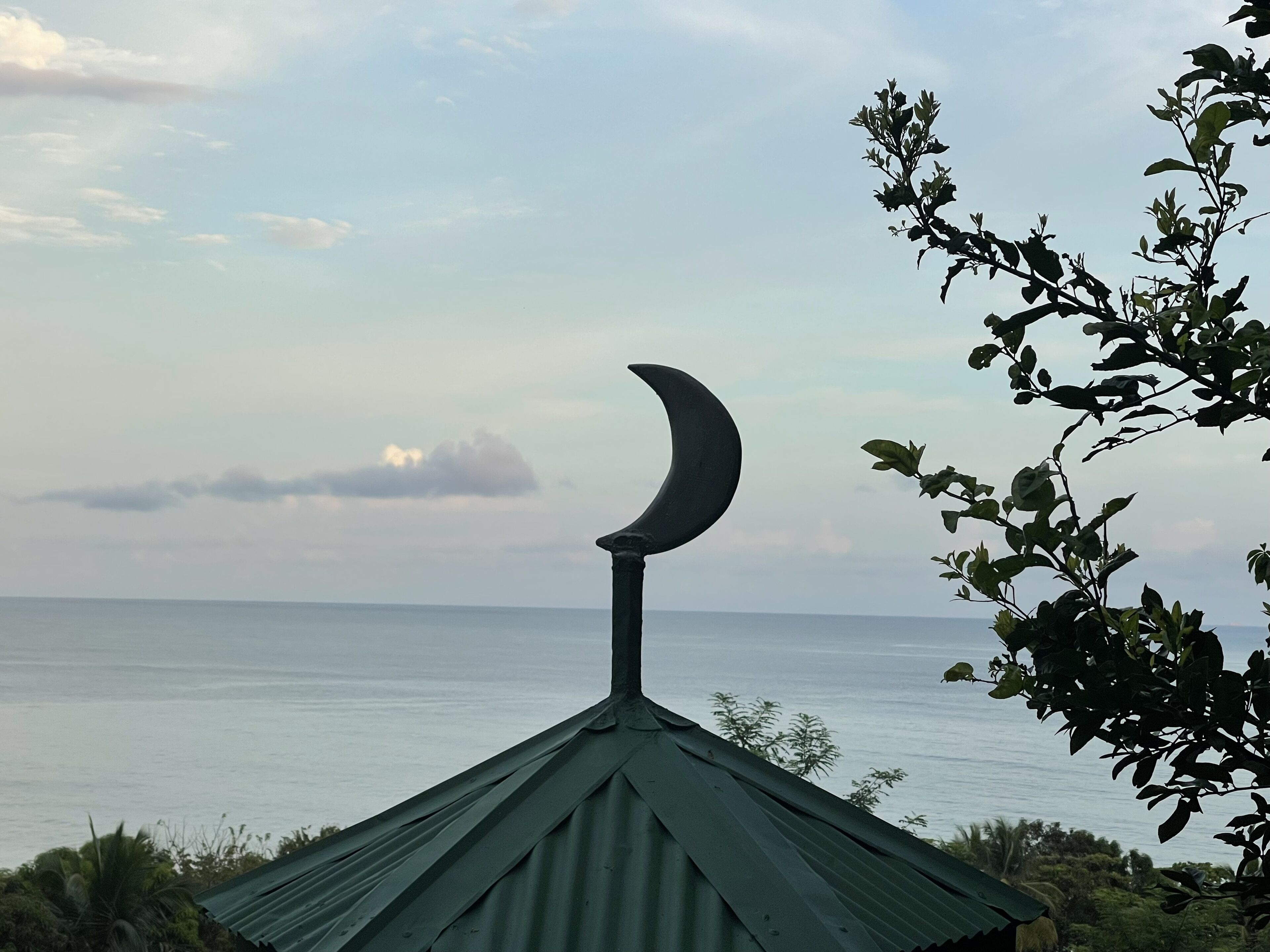 A building with a crescent moon roof, overlooking a body of water.