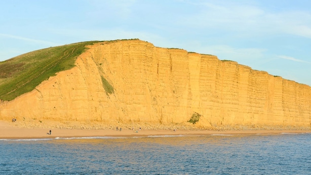 A coastal cliff with a beach and ocean. - Mead Cottage (Bridport)