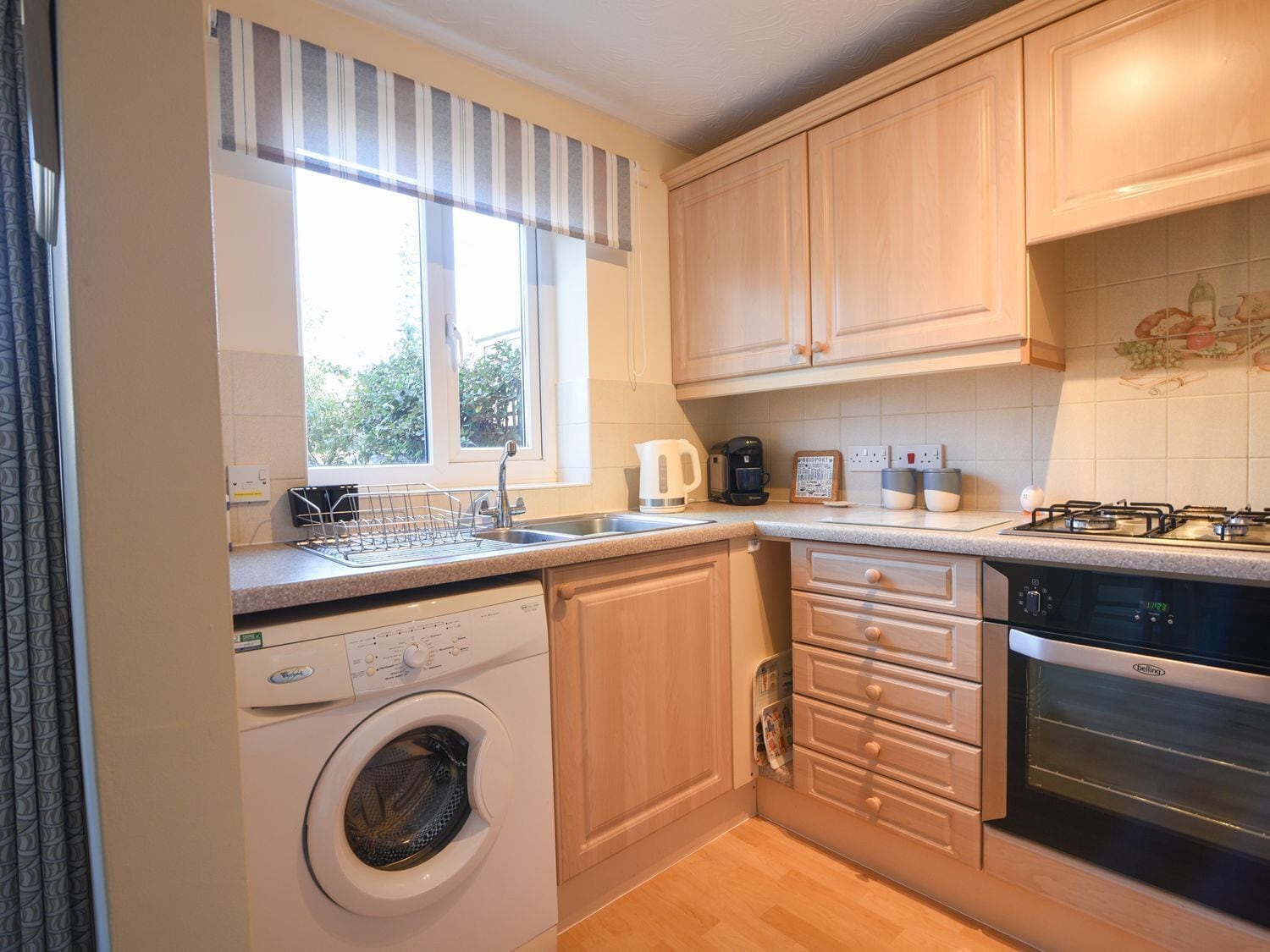 A compact kitchen with a washing machine, a coffee maker, and a gas stove.
