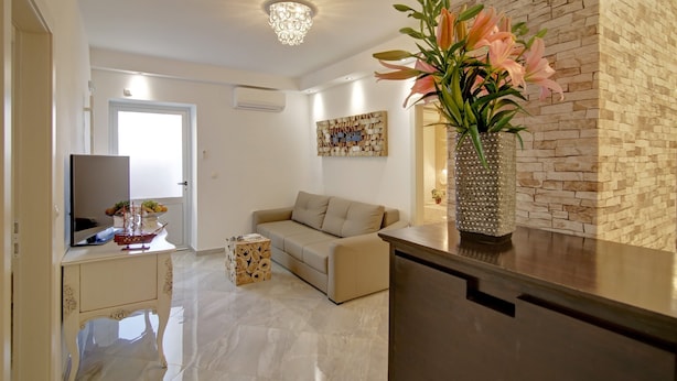 A modern living room with a beige sofa, a wooden coffee table, and a vase with flowers. - Villa Vanda - Deluxe Two Bedroom Apartment with Swimming Pool (Dubrovnik)