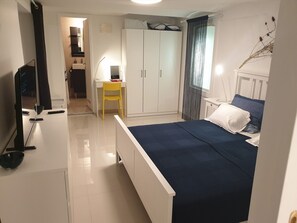 Une chambre à coucher comprenant un lit, un bureau, une chaise, une armoire et un téléviseur.