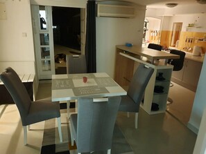Un espace de vie compact comprenant un coin repas, une kitchenette et un petit hall d’entrée.