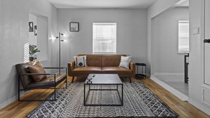 Una sala de estar moderna con un sofá de cuero, una mesa de centro y un tapete estampado.