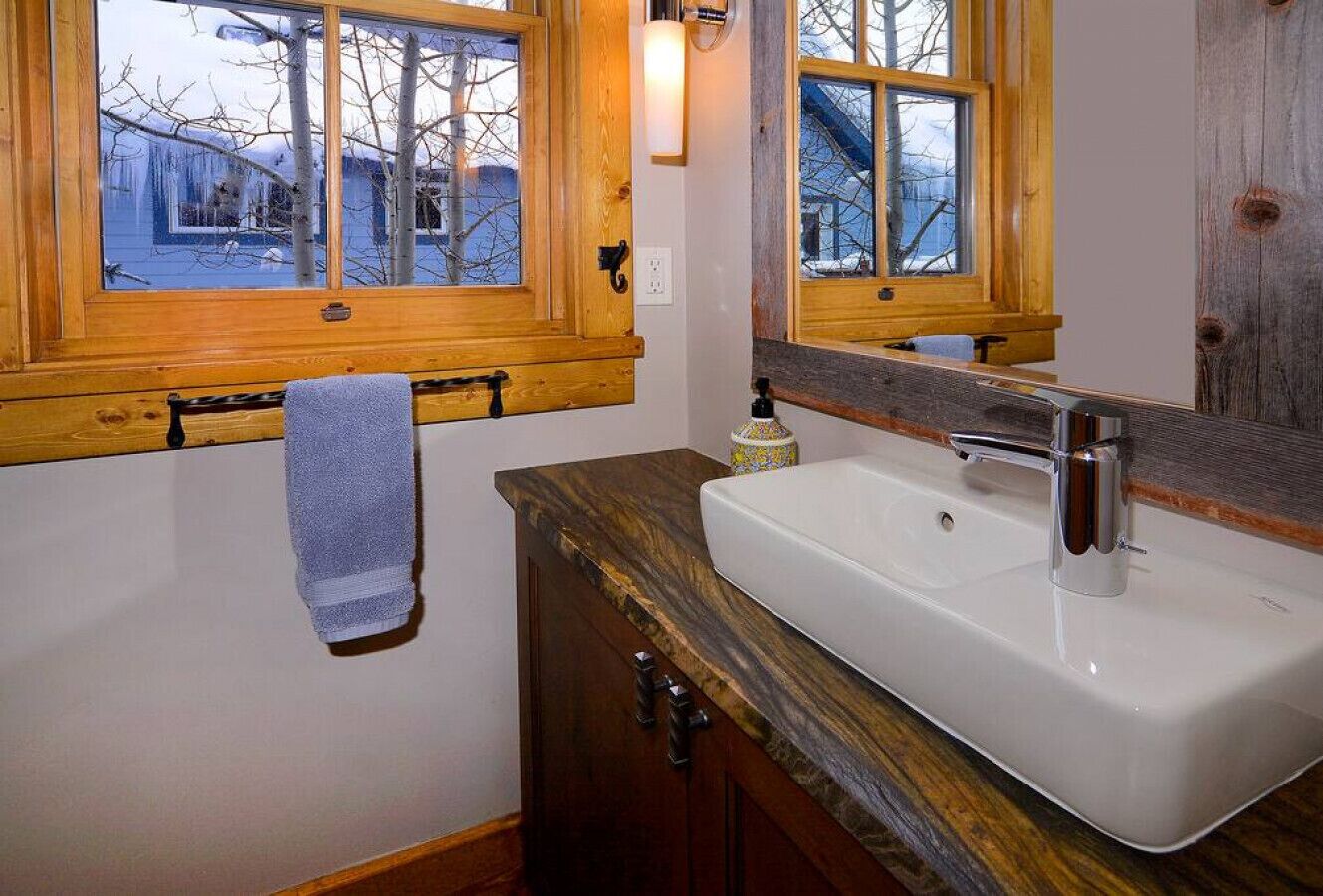 Une salle de bain avec un meuble-lavabo en bois, un lavabo blanc et une serviette suspendue à un porte-serviettes.