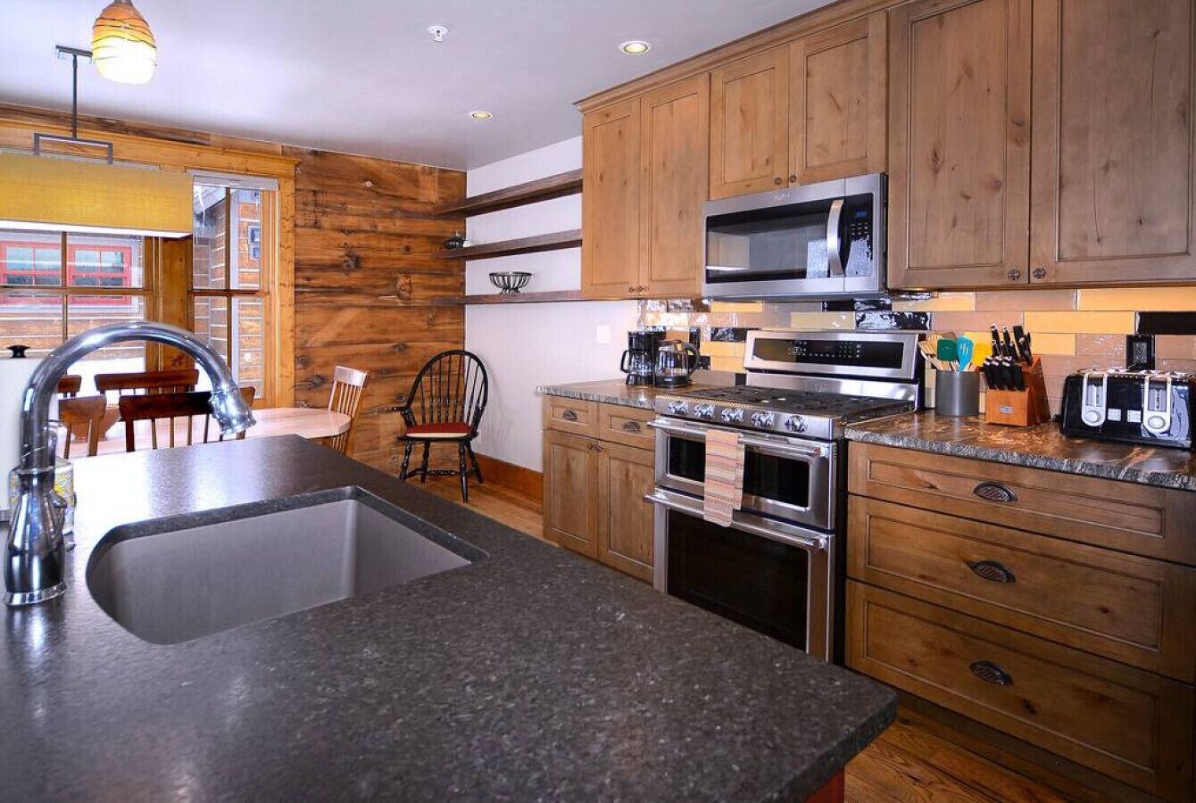 A modern kitchen with wooden cabinets, stainless steel appliances, and a granite countertop.