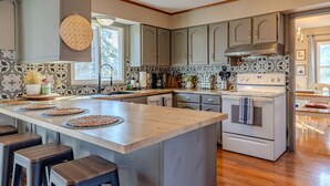 A kitchen with a central island, bar stools, and a stove.