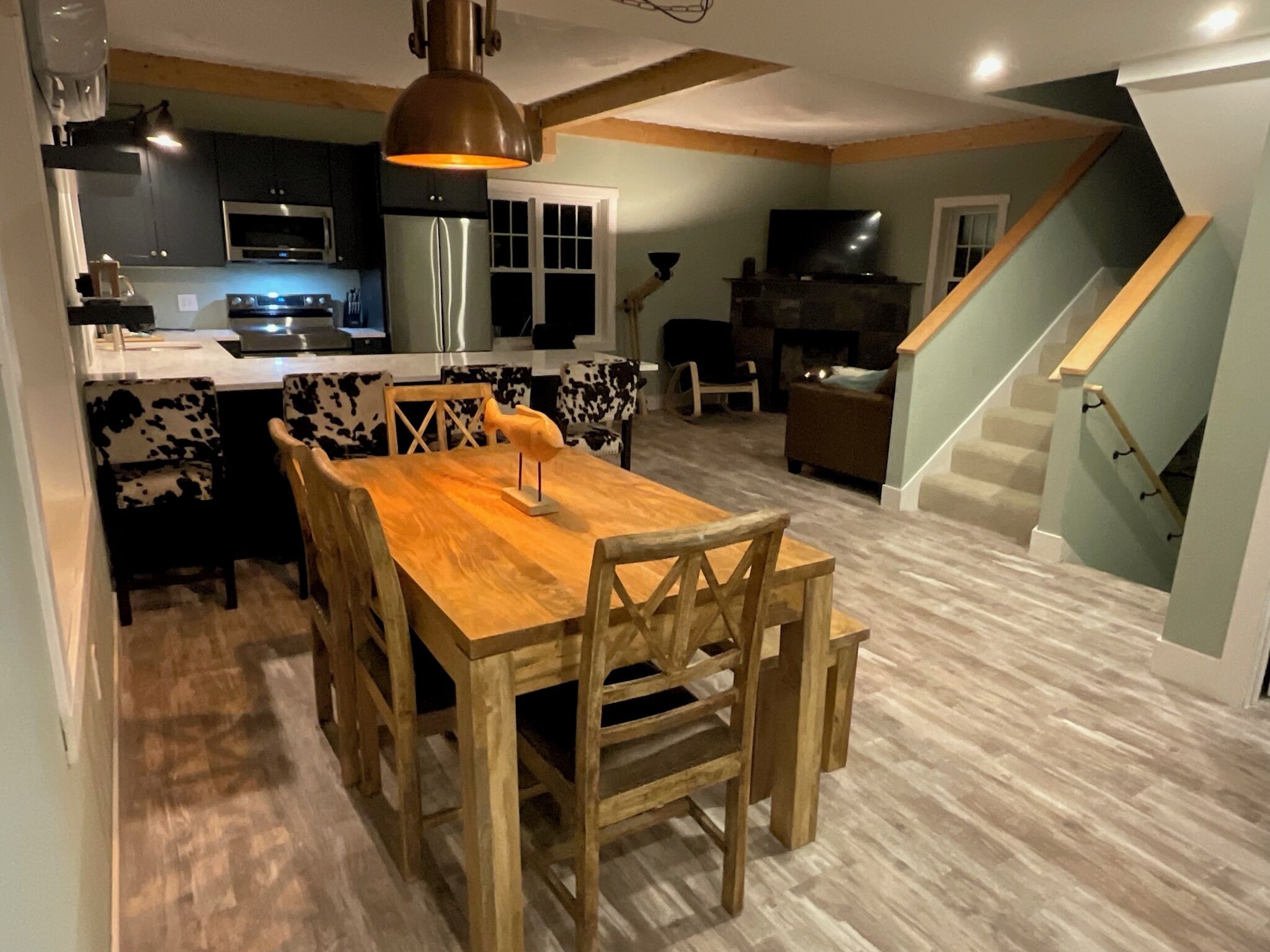 A modern kitchen with a dining area, a fireplace, and a staircase.