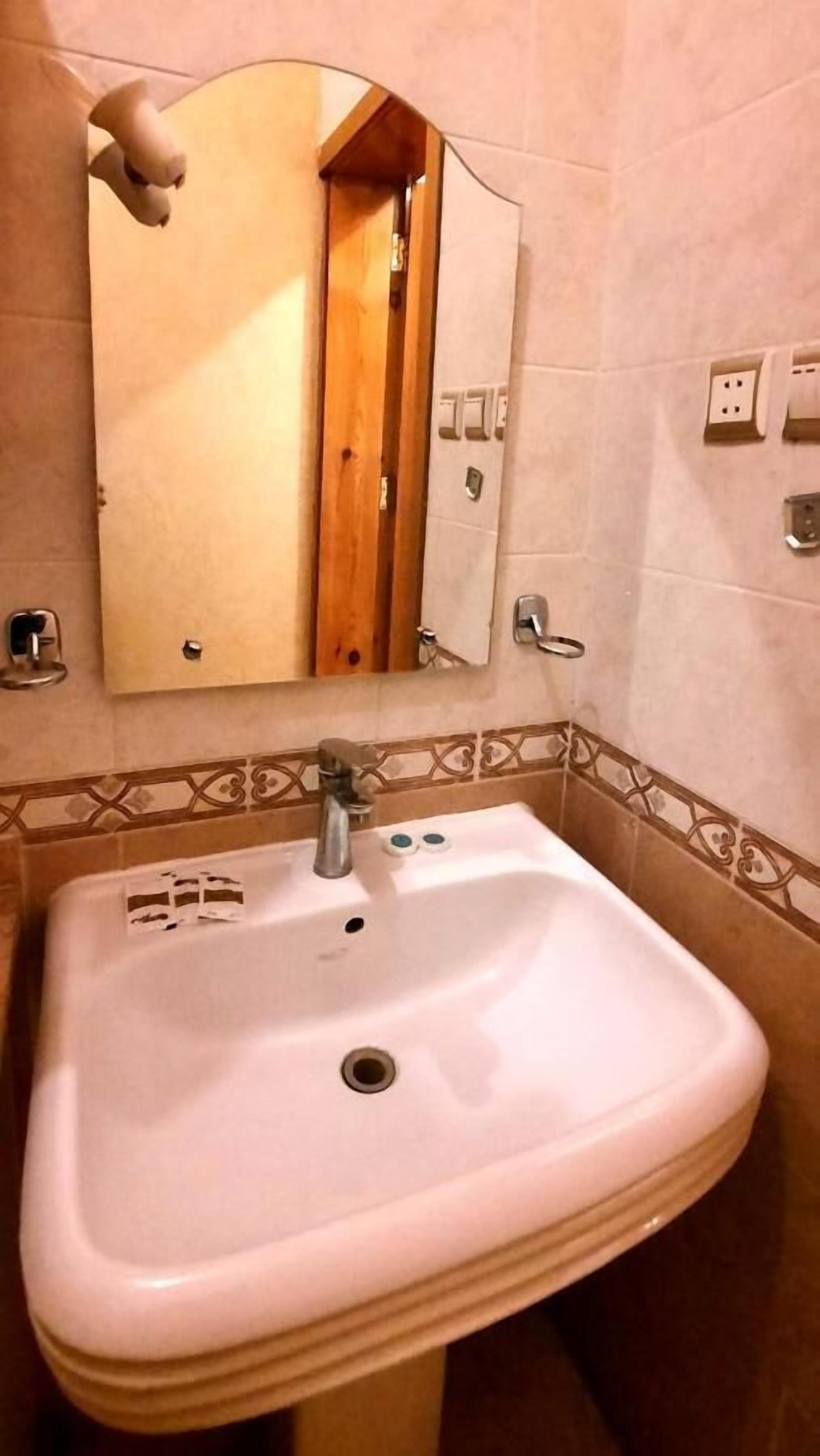 A bathroom with a white sink, a mirror, and a wooden door.