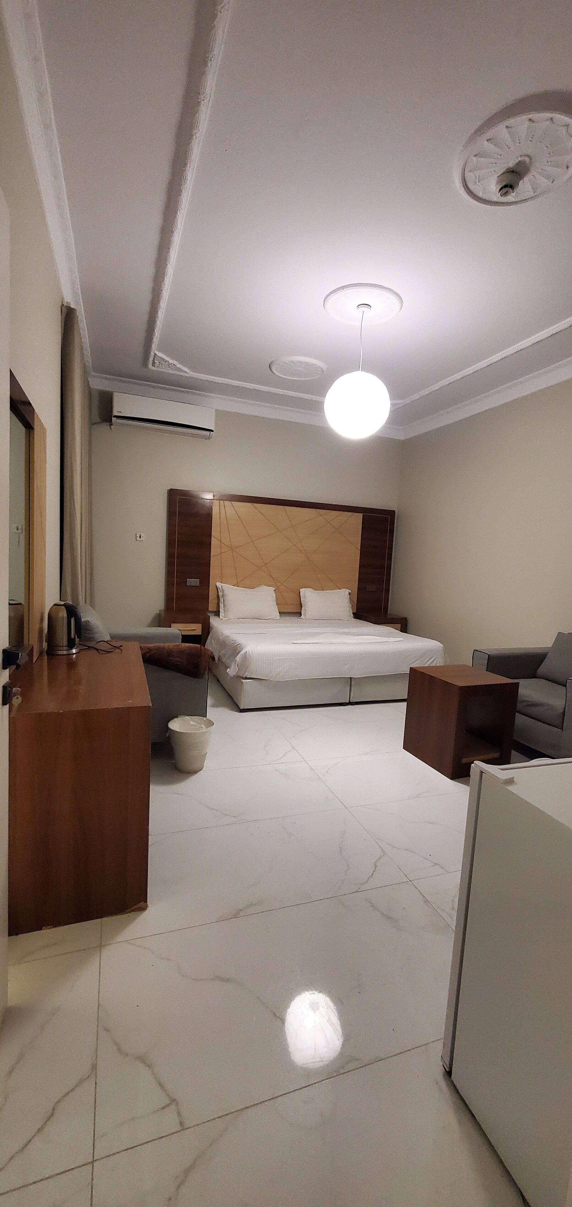 Une chambre d’hôtel équipée d’un lit, d’un bureau, d’une chaise, d’un canapé et d’une poubelle.
