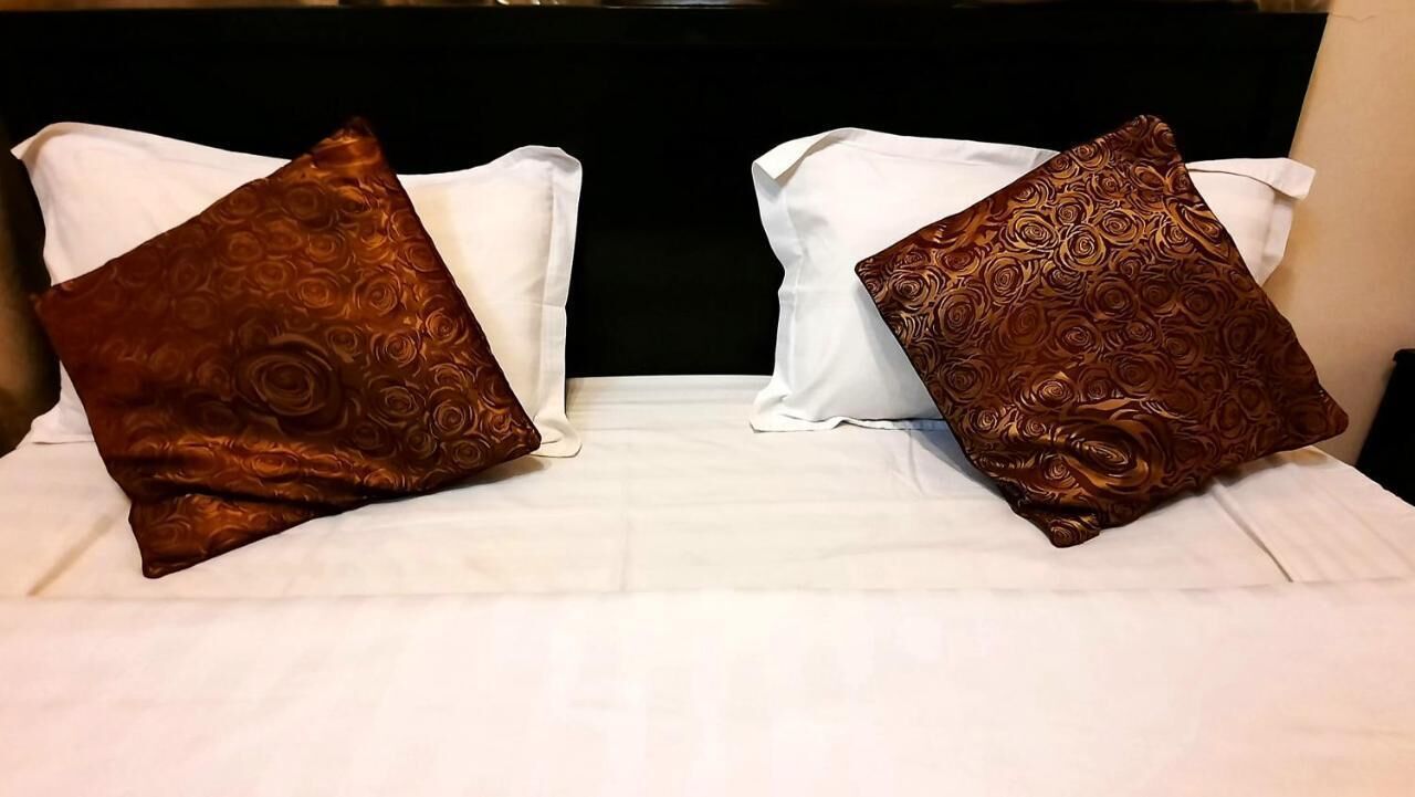 Una cama con dos almohadas, una blanca y otra marrón con estampado floral.