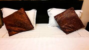 Una cama con dos almohadas, una blanca y otra marrón con estampado floral.
