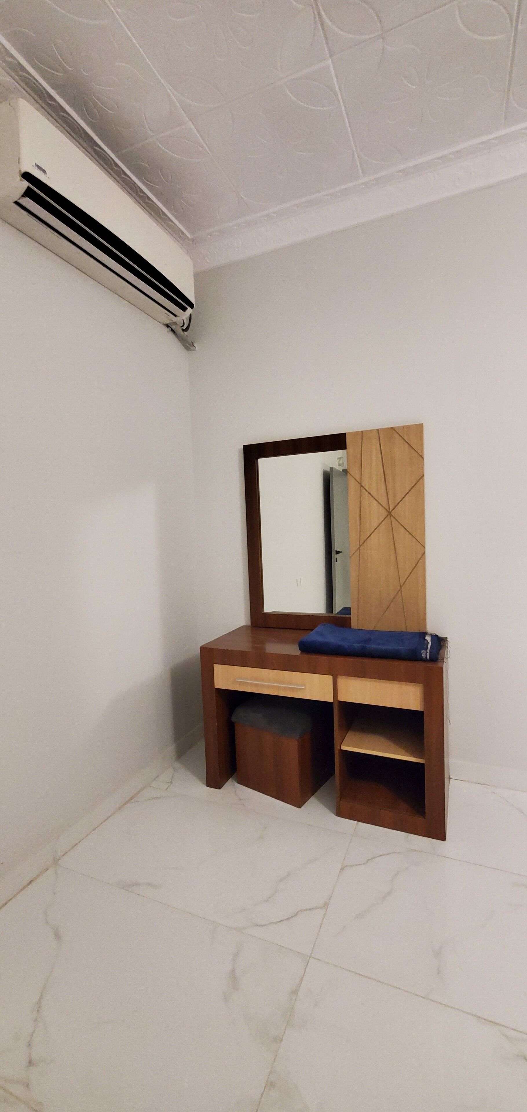 Una habitación con un escritorio de madera, un espejo y un equipo de aire acondicionado.