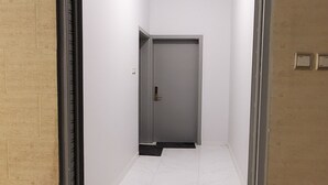 A hallway with a marble floor leading to a room with a door.