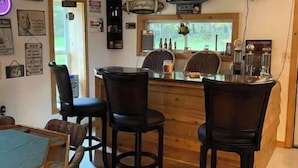 Zona de bar acollidora amb mobiliari de fusta, un televisor penjat a la barra i diverses decoracions a les parets.