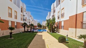 En bostadsbyggnad med en central innergård, en swimmingpool och en välskött gräsmatta.