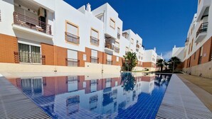 En swimmingpool med blå kakelplattor, omgiven av vita och röda byggnader med balkonger.