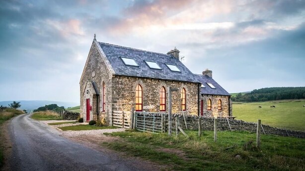 A stone building with a red door, multiple windows, and a sloped roof. - Chapel on the Hill (FOREST IN TEESDALE)