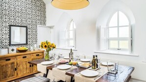 A dining area with a wooden table set for four, a vase of sunflowers, and a wooden cabinet with a mirror. - Chapel on the Hill (FOREST IN TEESDALE)