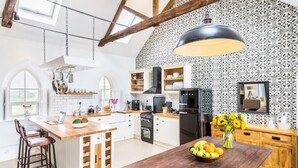 A modern kitchen with white cabinetry, a wooden island, and a black refrigerator. - Chapel on the Hill (FOREST IN TEESDALE)