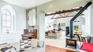 A spacious living room with a sofa, a fireplace, and a kitchen in the background. - Chapel on the Hill (FOREST IN TEESDALE)