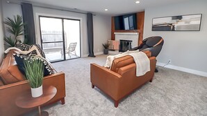 Un salon moderne avec un canapé, un fauteuil et une cheminée.
