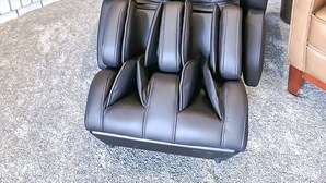 Un fauteuil de massage doté d’un panneau de commande, un tableau encadré accroché au mur et une petite table ronde sur laquelle est posé un objet décoratif.
