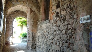 A narrow stone corridor with an arched doorway, a window with bars, and a sign reading "Strada Regia". - Dream view - Spacious apartment with large garden (Lezzeno)