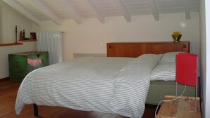 A bedroom with a bed, a wooden headboard, a radiator, a green chest of drawers, and a red lamp. - Dream view - Spacious apartment with large garden (Lezzeno)
