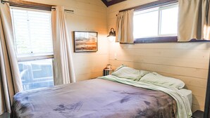 Ein Zimmer mit einem Bett, einem Nachttisch, einer Lampe und einem Bild an der Wand.