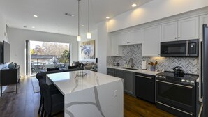 Une cuisine moderne dotée d’un grand îlot central, d’appareils électroménagers intégrés et d’un dosseret en carreaux disposés en motif chevron.