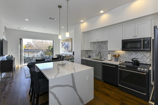 A modern kitchen with a large island, built-in appliances, and a herringbone tile backsplash.