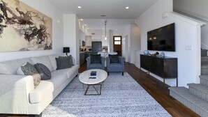 Un salon moderne avec un canapé, des fauteuils, une table basse et un téléviseur.