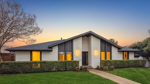 A modern two-story house with a well-maintained lawn, a clear sky, and a visible address number. - Zen Back Yard with Hot Tub & Firepit: Spa at Home (Dallas)