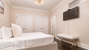 Ein Schlafzimmer mit einem Bett, einer Bank und einem an der Wand befestigten Fernseher.