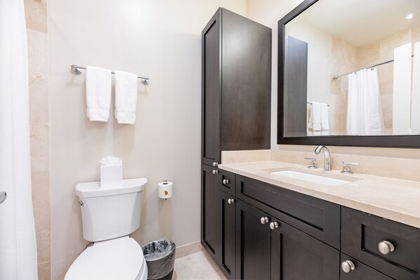 Un baño moderno con inodoro, lavamanos y armarios oscuros.