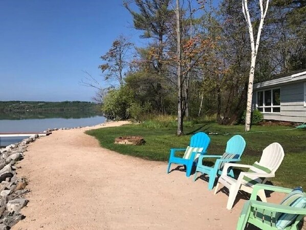 Sandy beach with seating and bonfire pit. - Beachfront Cottage on Little Traverse Lake (Cedar)