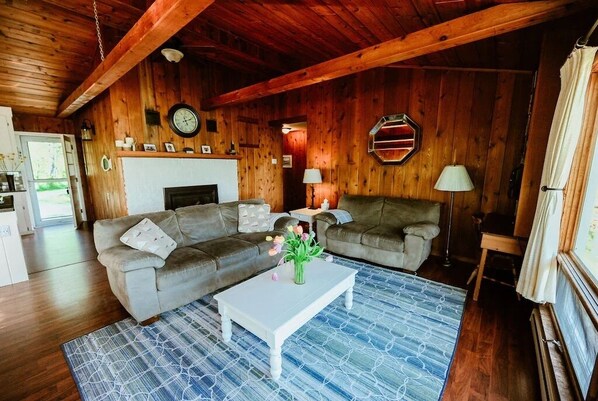 Main living with cozy gas fireplace and open view of lake through large windows - Beachfront Cottage on Little Traverse Lake (Cedar)