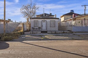A residential house with a gated entrance, a small porch, and a clear sky.
