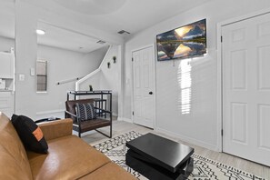 A modern living room with a brown leather sofa, a black coffee table, and a TV mounted on the wall.
