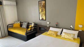 Une chambre d’hôtel avec deux lits, une décoration aux tons gris et jaune, un climatiseur fixé au mur, une œuvre d’art encadrée et une petite plante en pot.