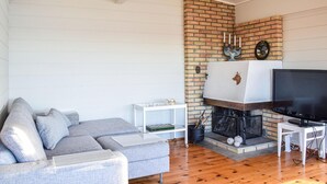 A living room with a fireplace, a sofa, a TV, and a small table. - Beach front home in Nordtveitgrend with WiFi (Nordtveitgrend)