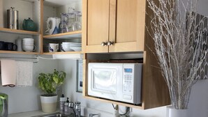 Una cocina con armarios de madera, microondas, pileta y una planta en maceta.