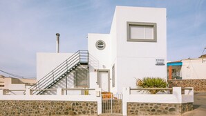 Een modern gebouw met een witte gevel, een stenen basis, een trap en een klein raam.