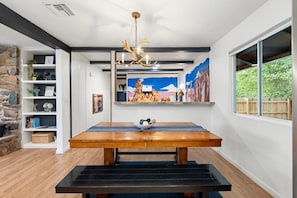 Enjoy meals in this dining area with a table for four, a bowl of fresh fruit, and a beautiful painting above.