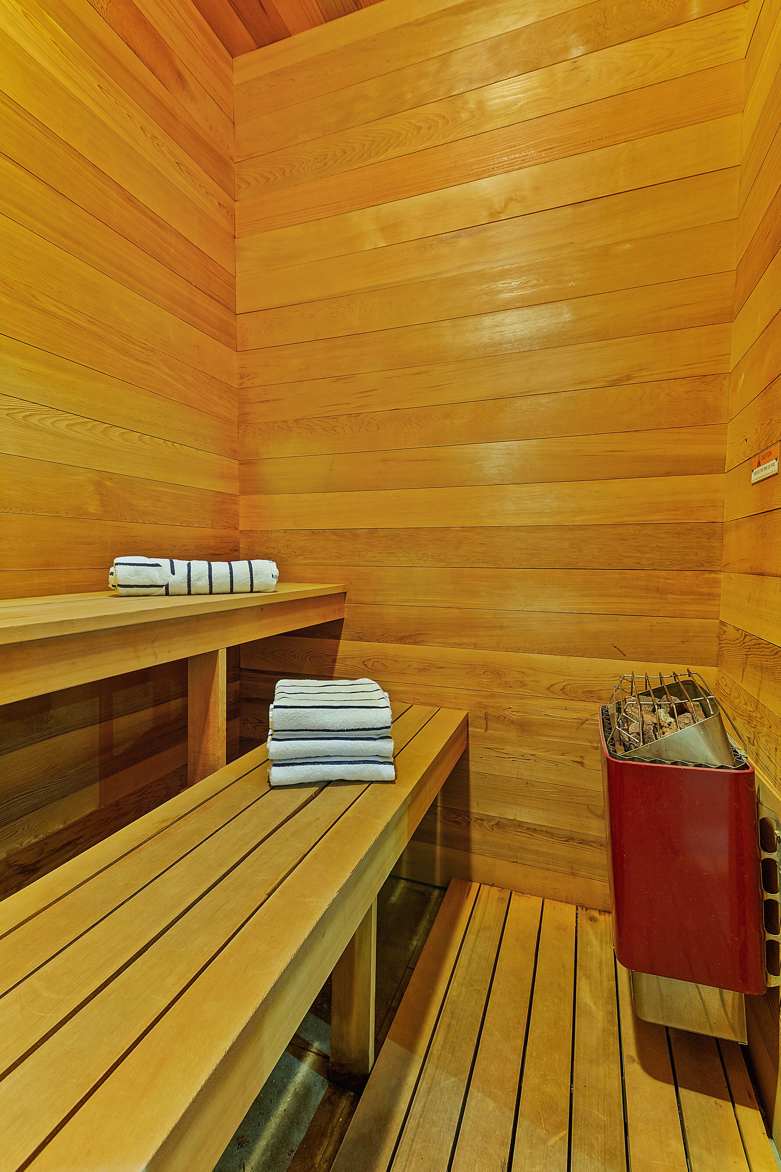 Un sauna en bois, doté de bancs et d’un appareil de chauffage rouge.