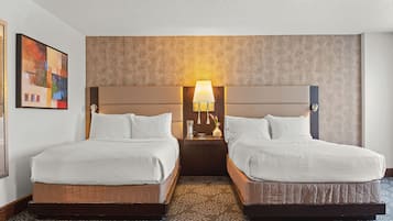Une chambre d’hôtel avec deux lits, une table de chevet avec une lampe et un tableau au mur.