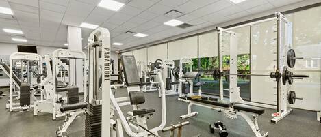Une salle de sport équipée de divers appareils d’entraînement, notamment des machines de musculation, des bancs et des haltères.